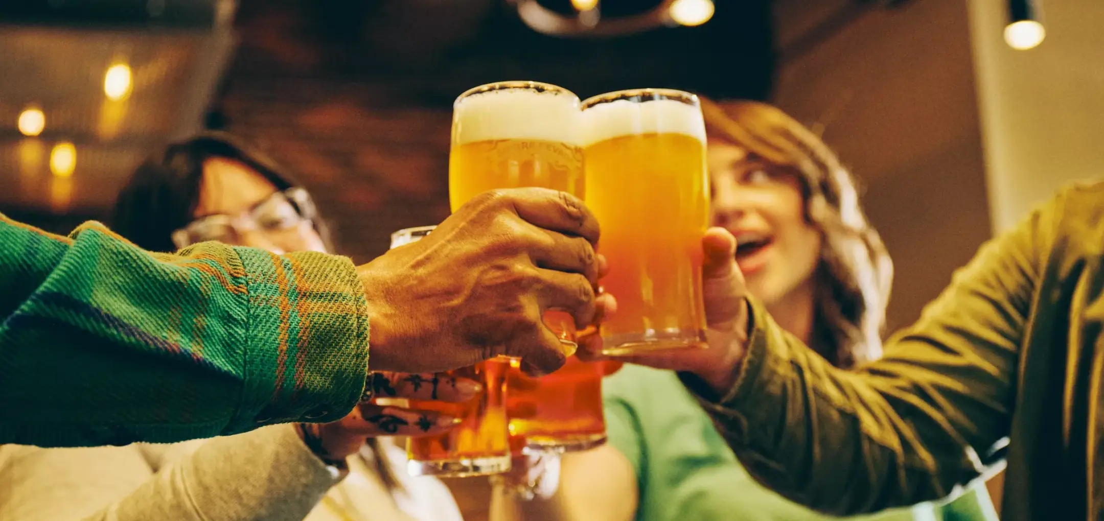 Hands holding glasses of Sierra Nevada beer being cheersed inside