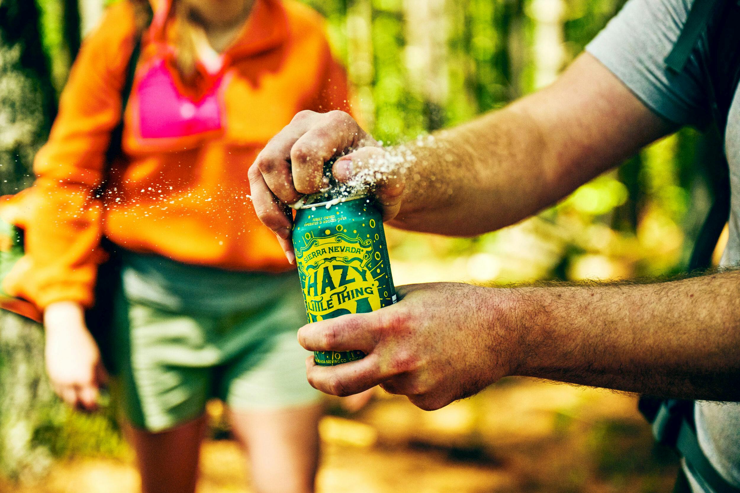 A hiker cracks open a cold can of Hazy Little Thing.