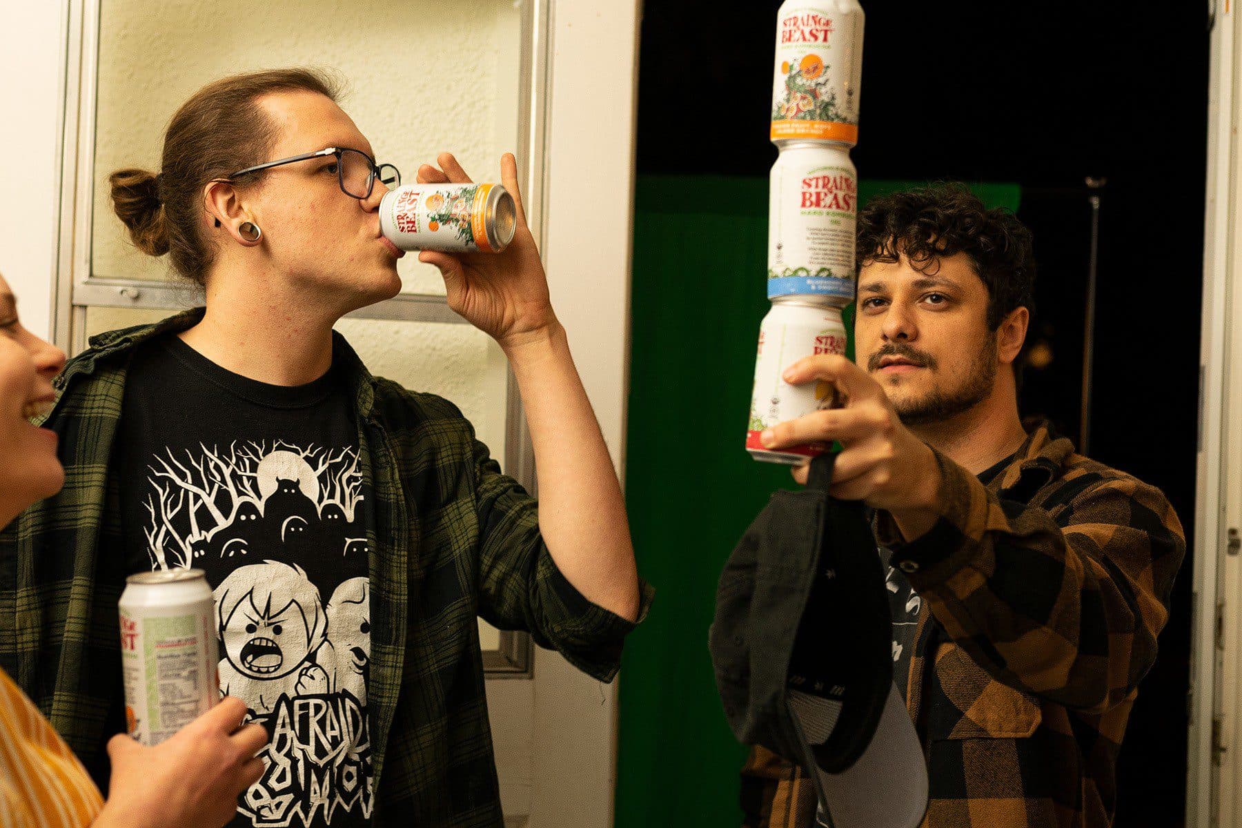 A young man balancing a tower of three Strainge Beach hard kombucha cans