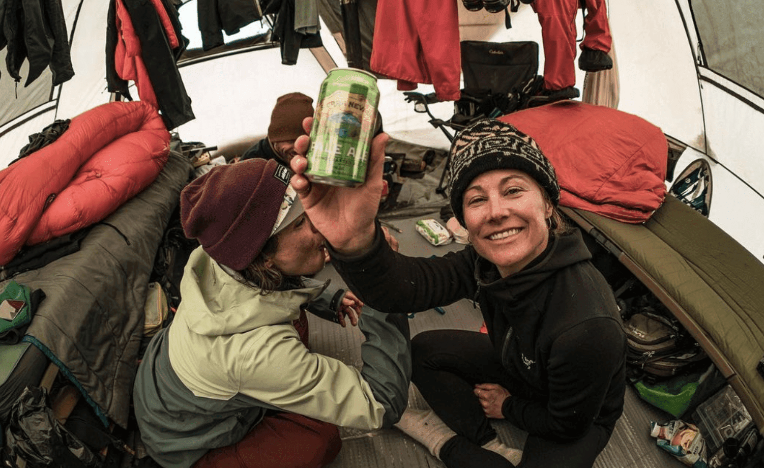 Robin holding a can of Pale Ale in a tent