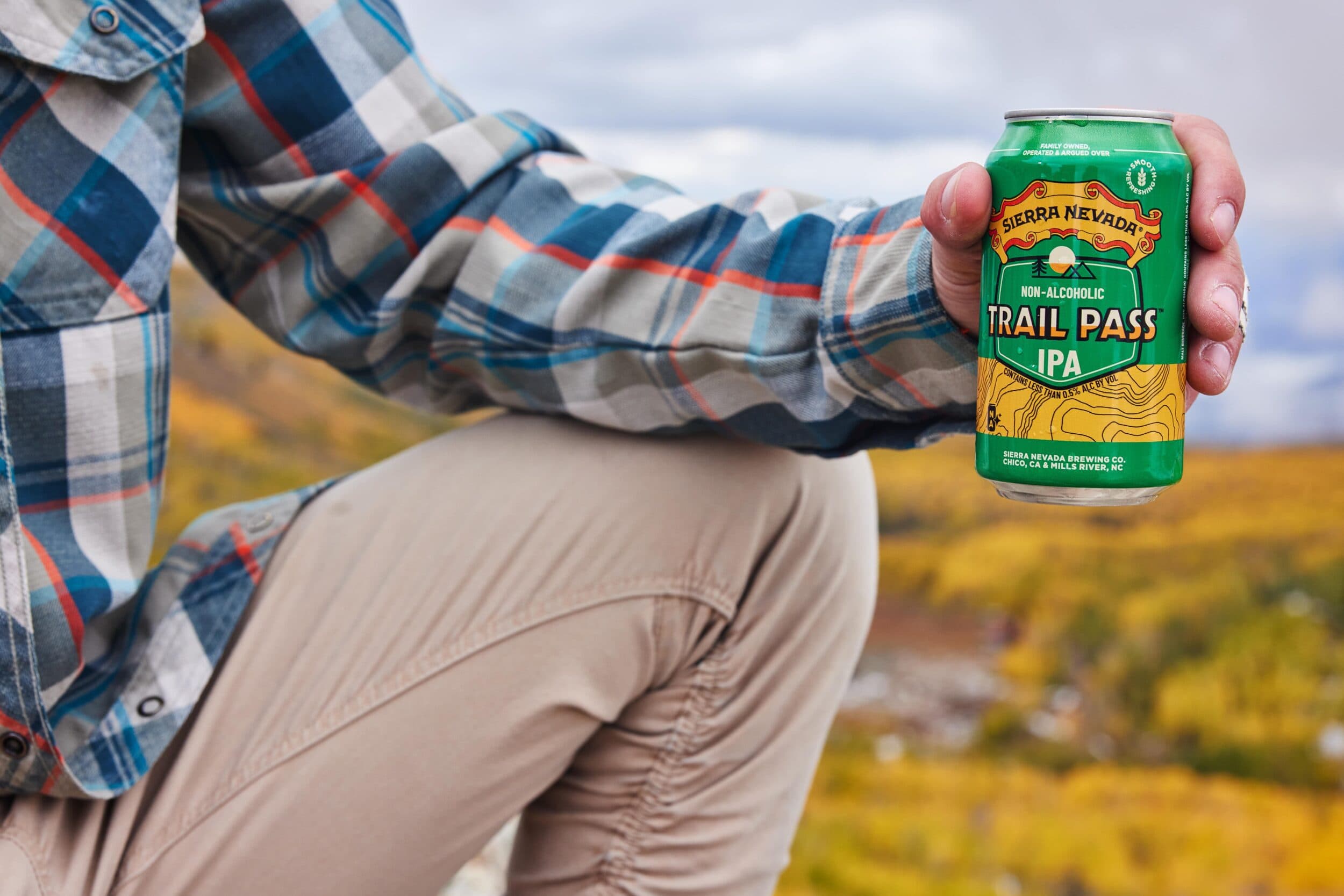 Trail Pass IPA can being held outside by hiker