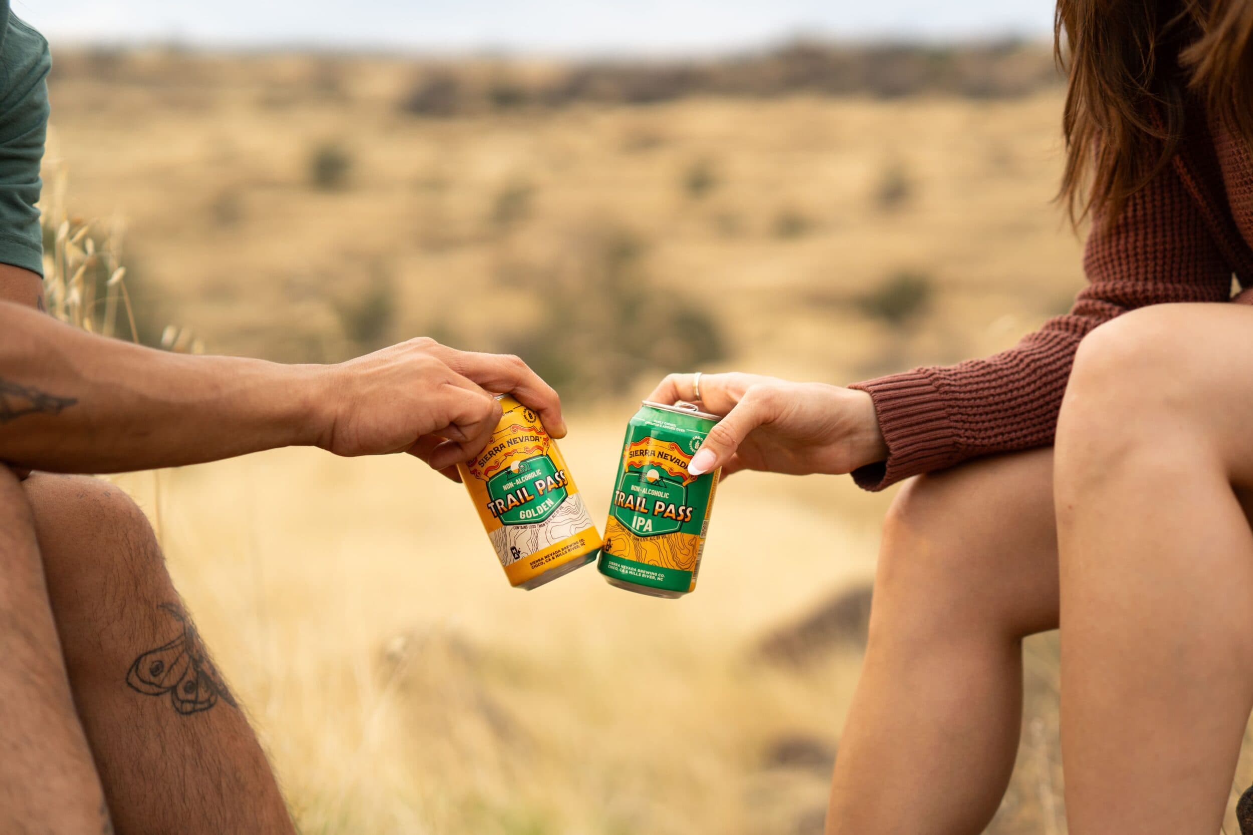 Trail Pass cans being cheersed outside