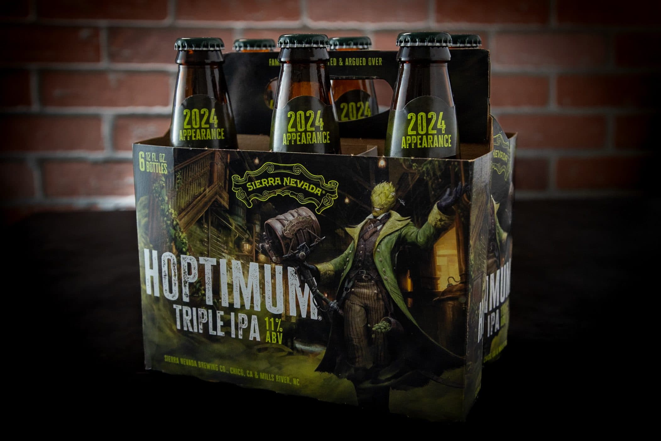 A six-pack of Hoptimum Triple IPA on a dark table with a brick wall background