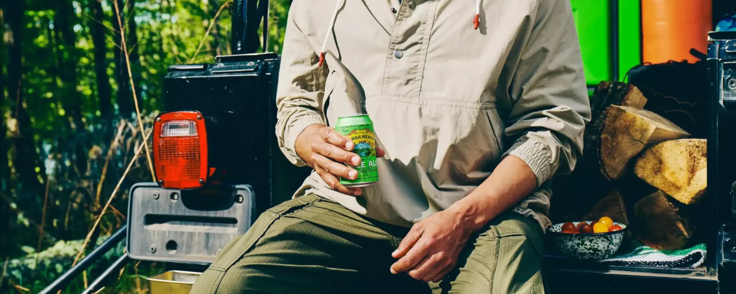 Person holding Pale Ale can while sitting on tailgate.