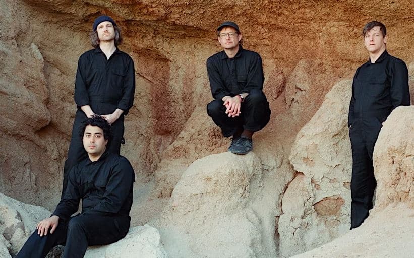 STRFKR band sitting on rocks