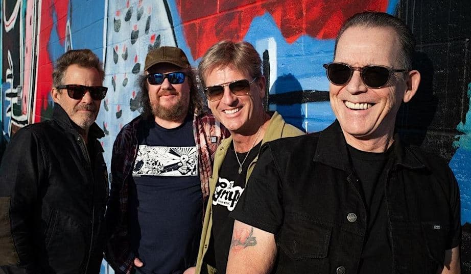 Tommy Castro band members leaning against a painted wall