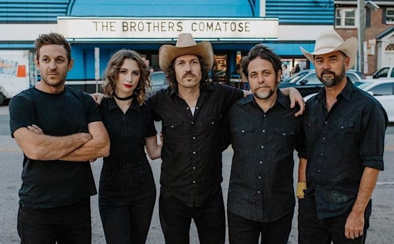 The brothers comatose band standing outside of a venue with their band name on the front