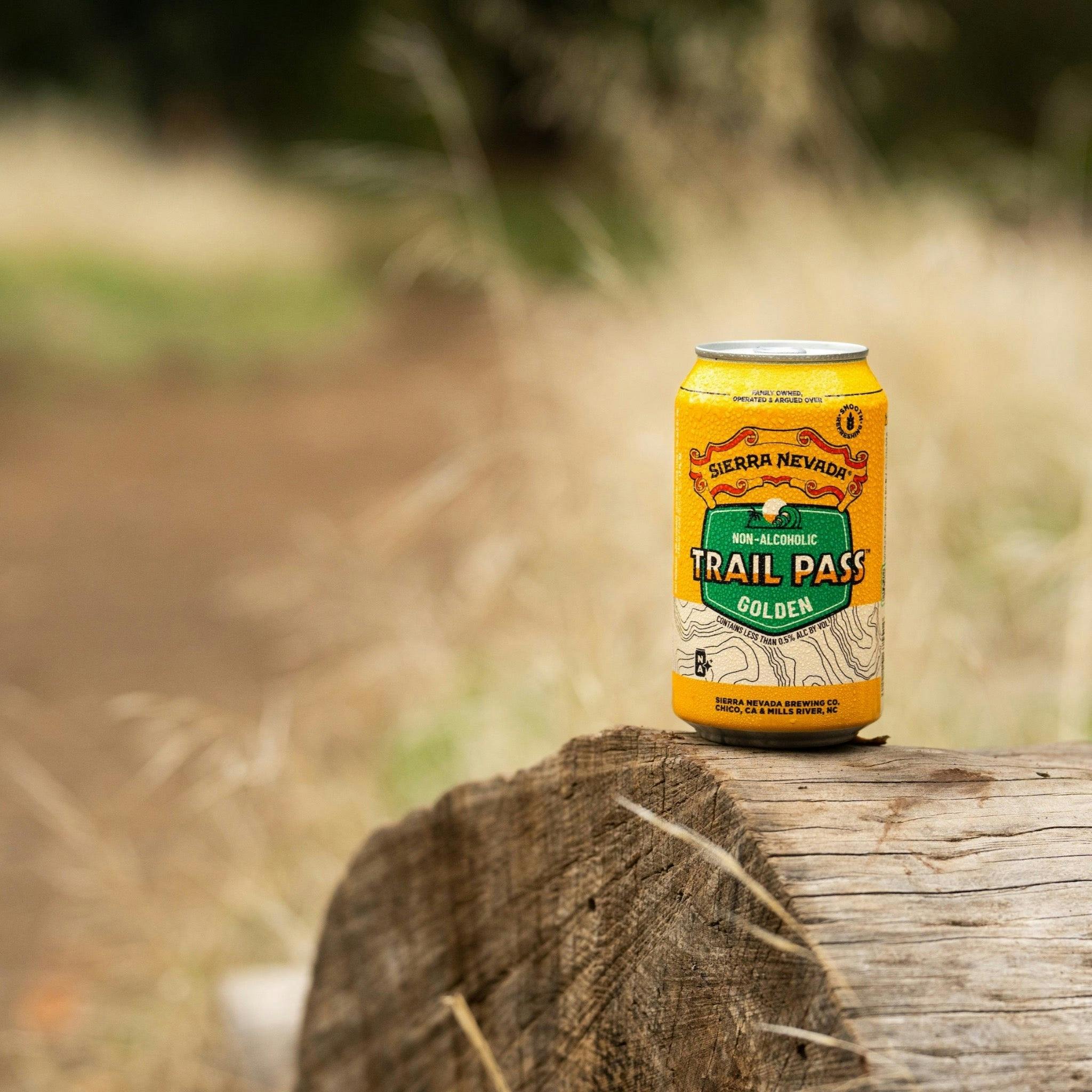 Sierra Nevada Brewing Co. Trail Pass Golden Non-Alcoholic Brew - A refreshing can of Trail Pass Golden sits atop a fallen log near a hiking trail