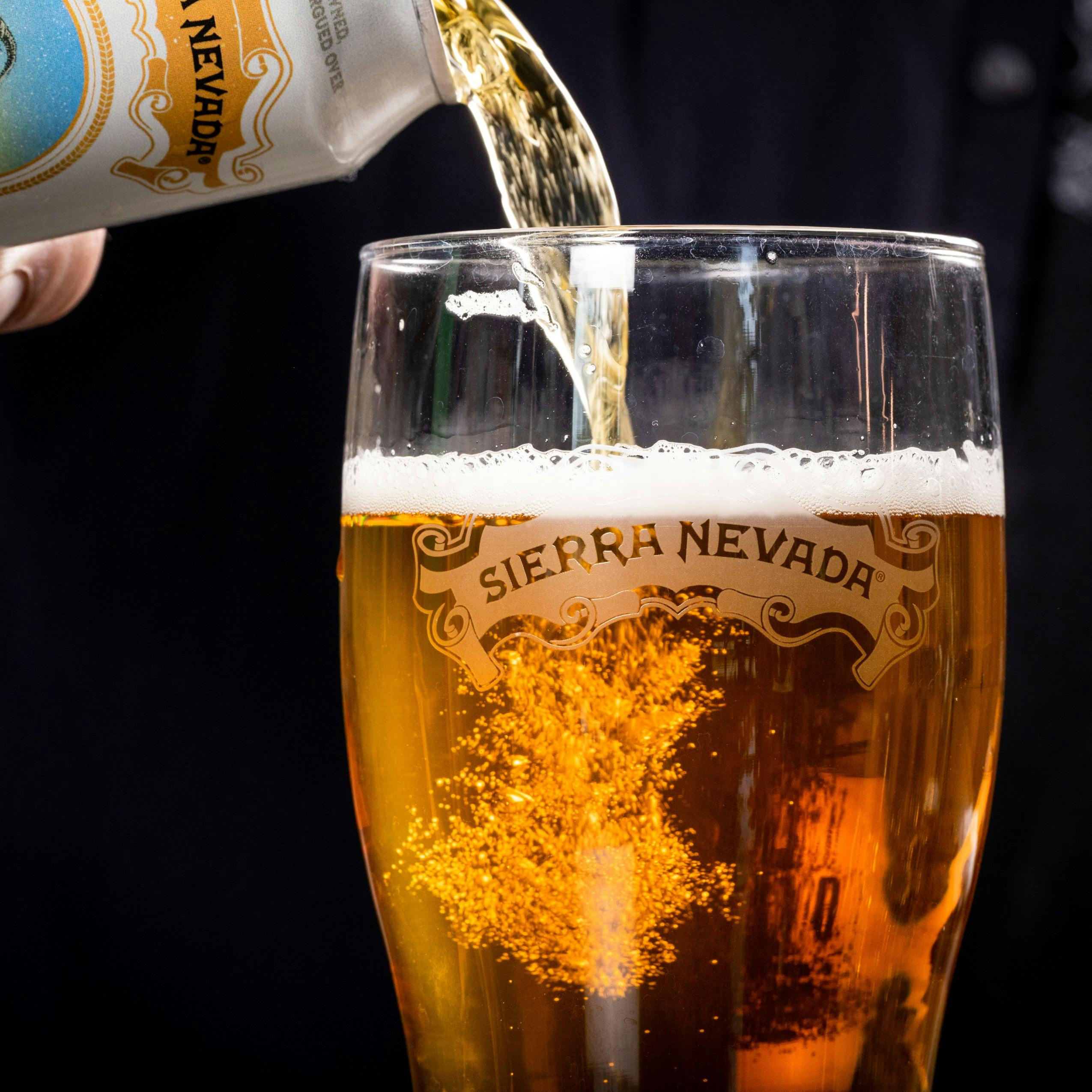 A close-up of the pour from a can of Sierra Nevada Pale Bock into a pint glass featuring the Sierra Nevada scroll logo.