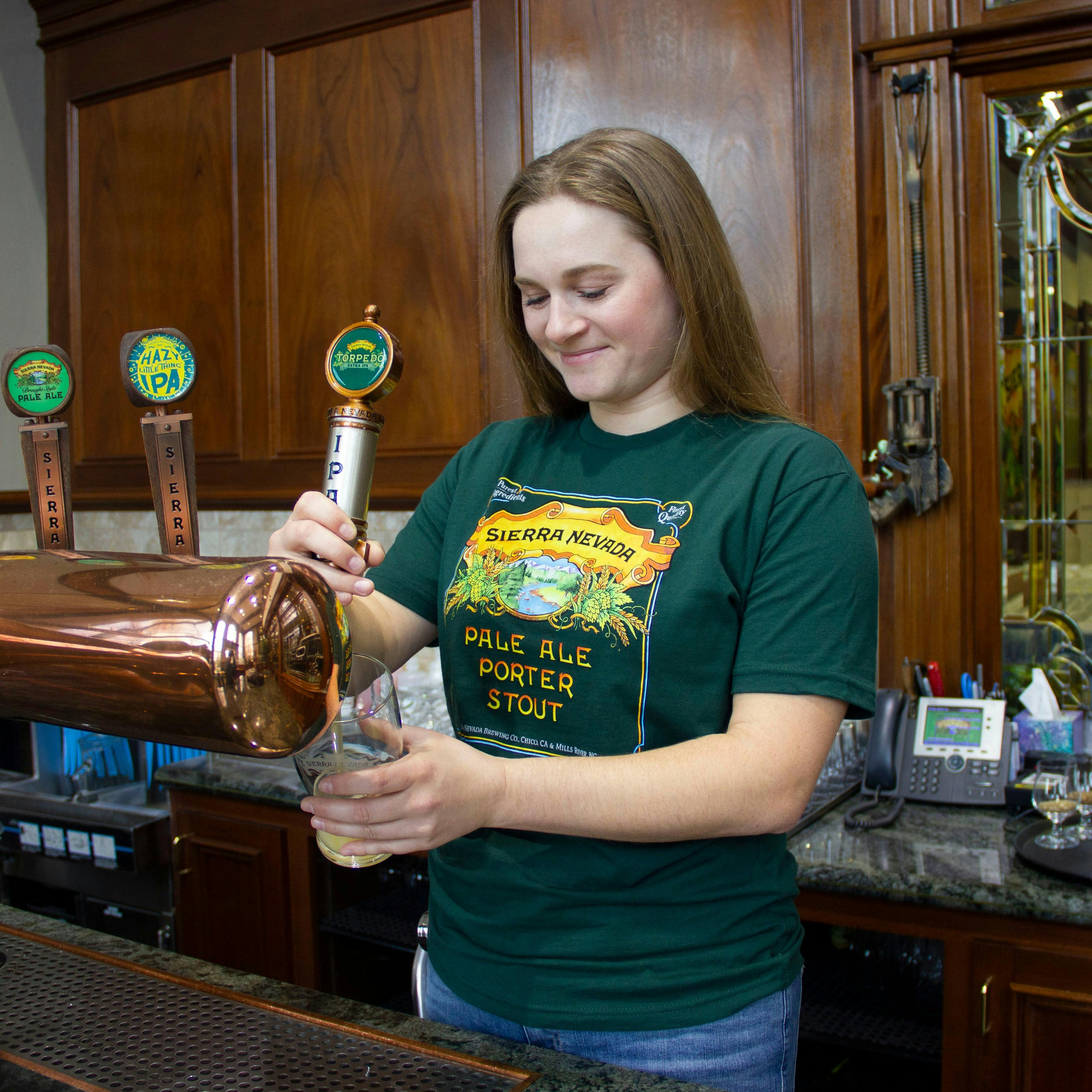Sierra Nevada Pale Ale - Porter - Stout short sleeve green t-shirt worn by a woman in a brewery filling a pint glass from the tap