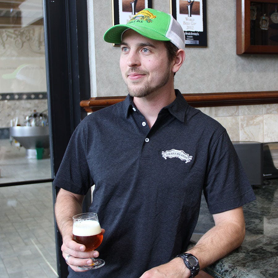 Sierra Nevada Recover Polo with scroll logo worn by a man drinking a beer in a brewery
