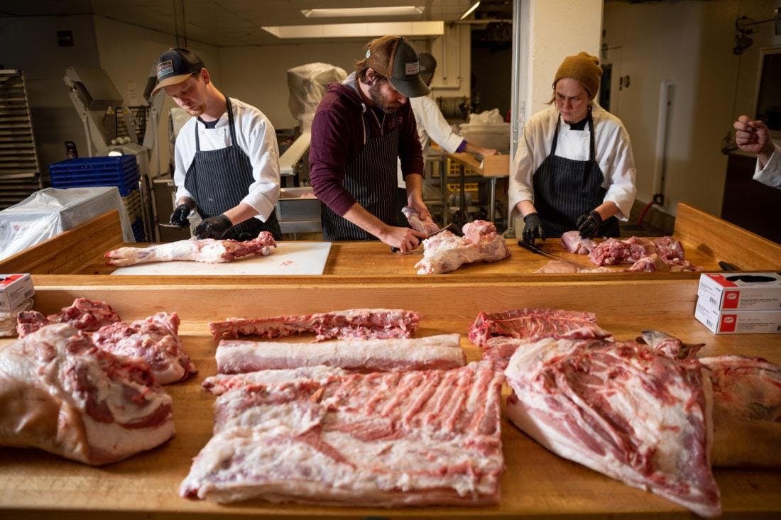 three cooks butchering meat