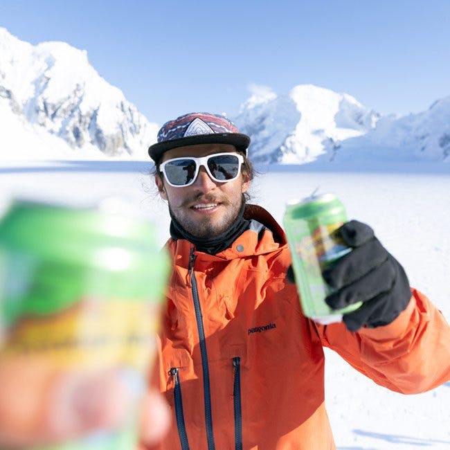 Rafael Pease holding beer in snowy mountains
