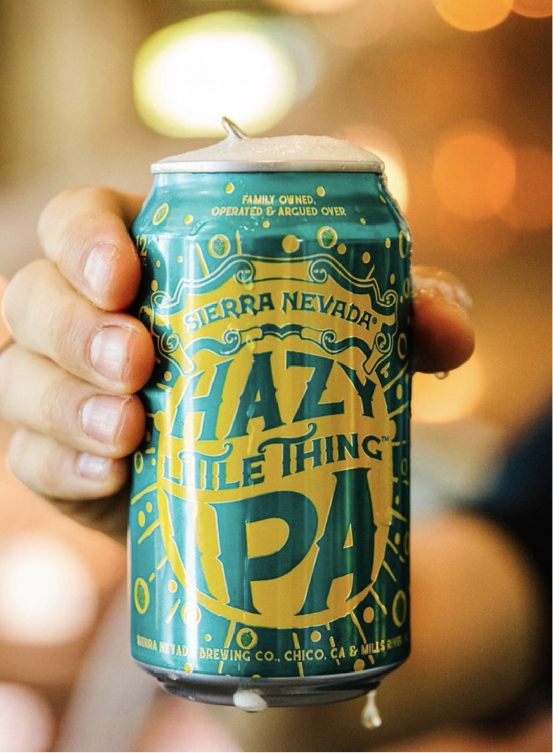 A man's hand holding a can of Hazy Little Thing IPA beer