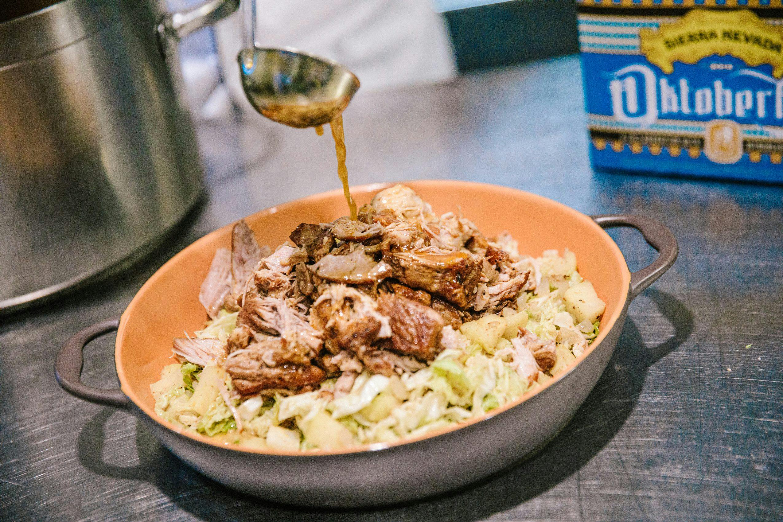 Chef holding a plate of braised pork and cabbage next to Oktoberfest beer