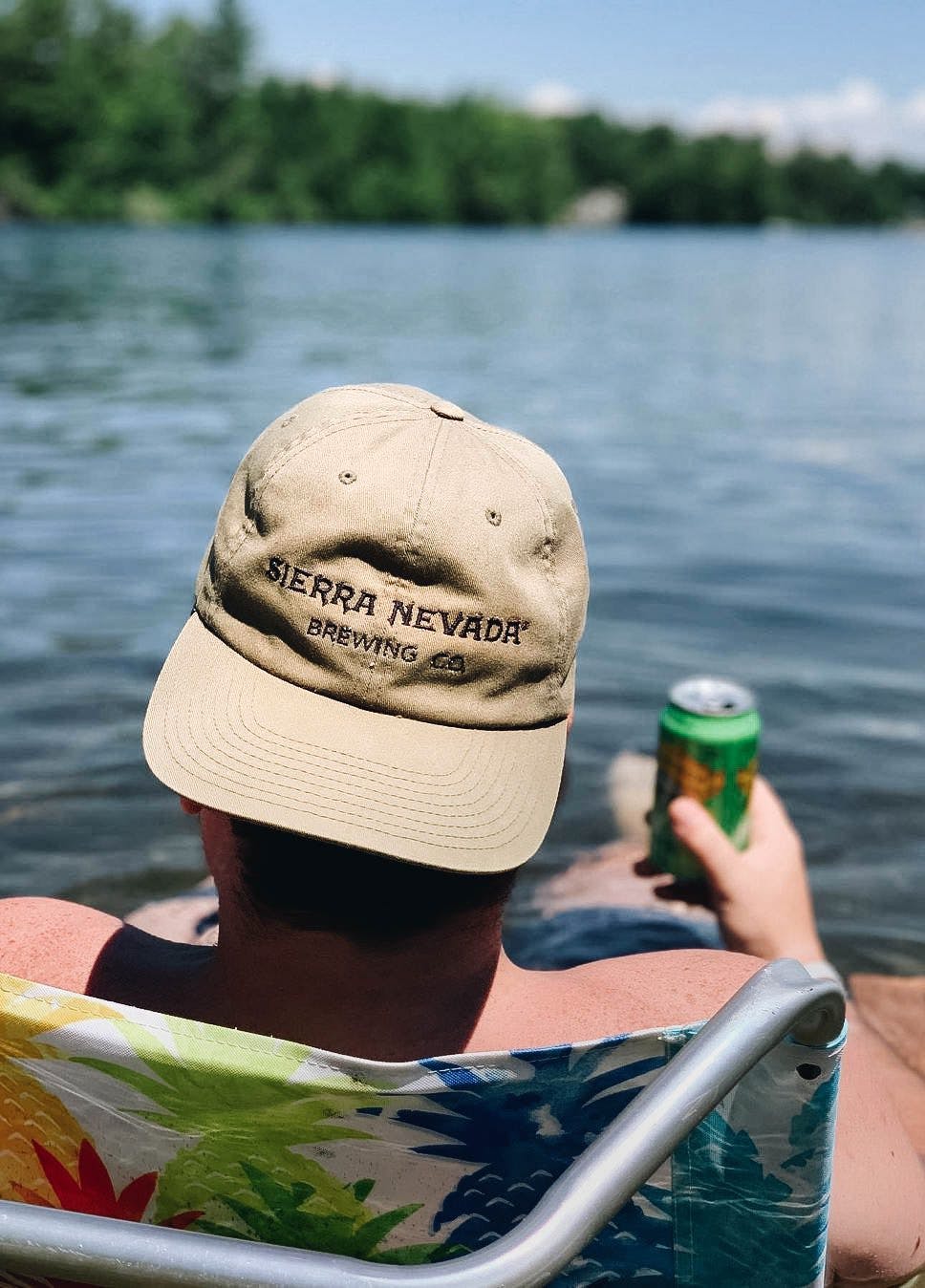 Man wearing Sierra Nevada hat holding Pale Ale at lake