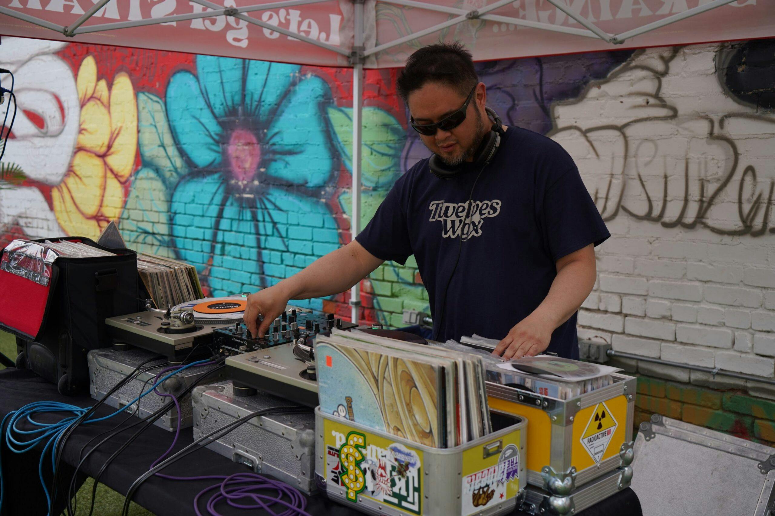 DJ mixes outside under a Strainge tent
