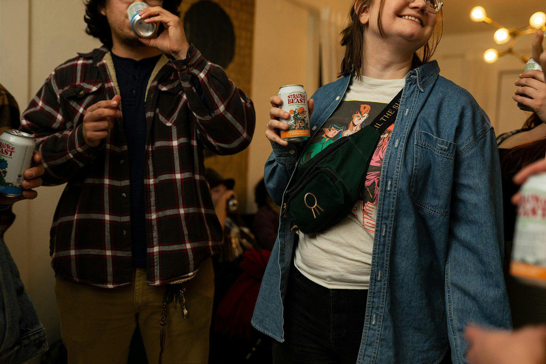 Two friends holding cans of Strainge Beast at a house party