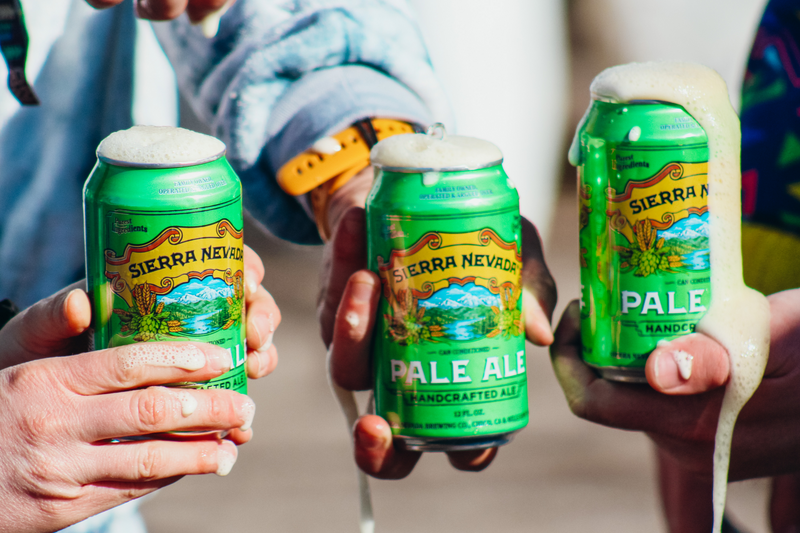 three hands holding cans of Pale Ale