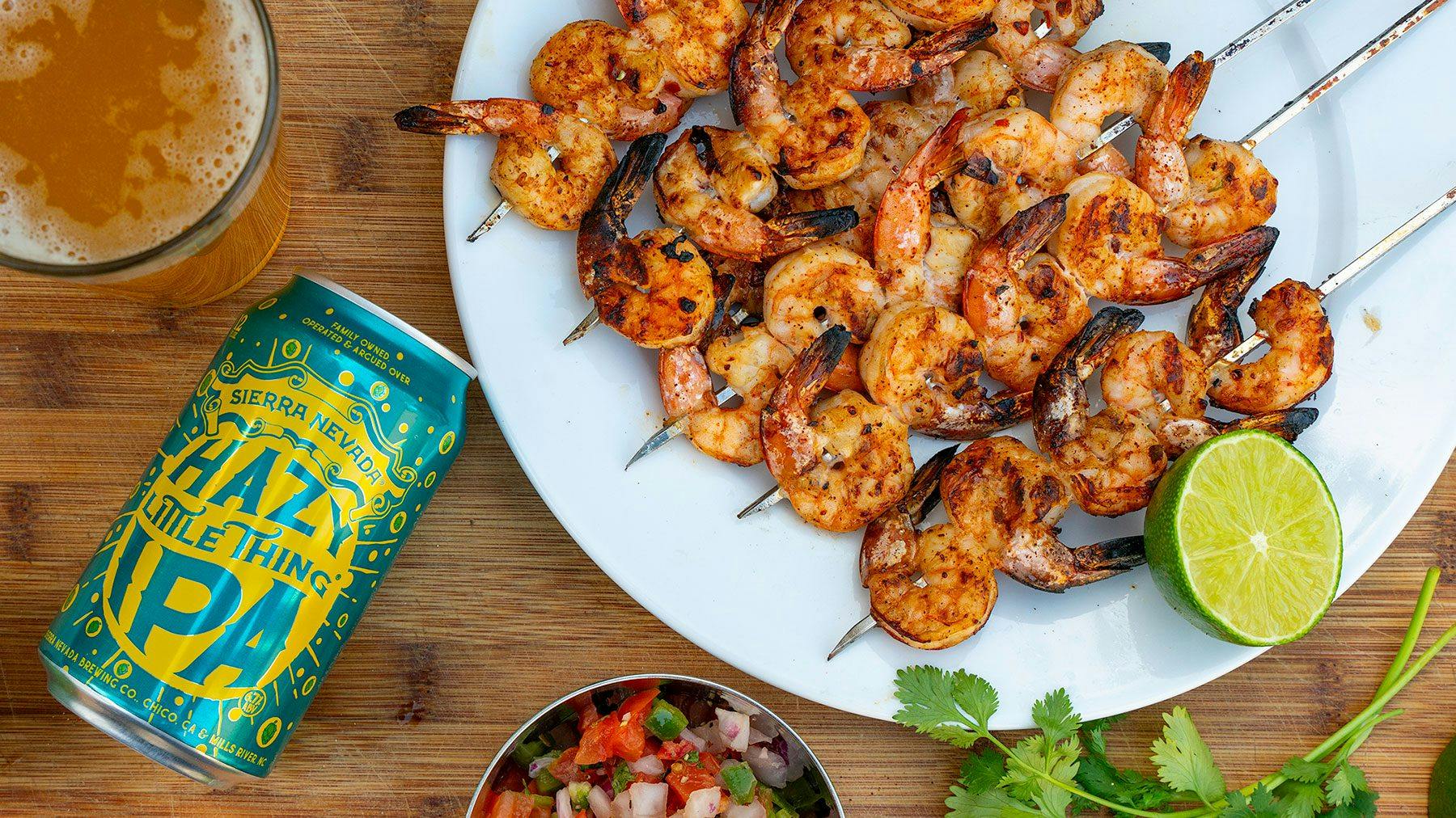 A can of Hazy Little Thing next to grilled shrimp skewers