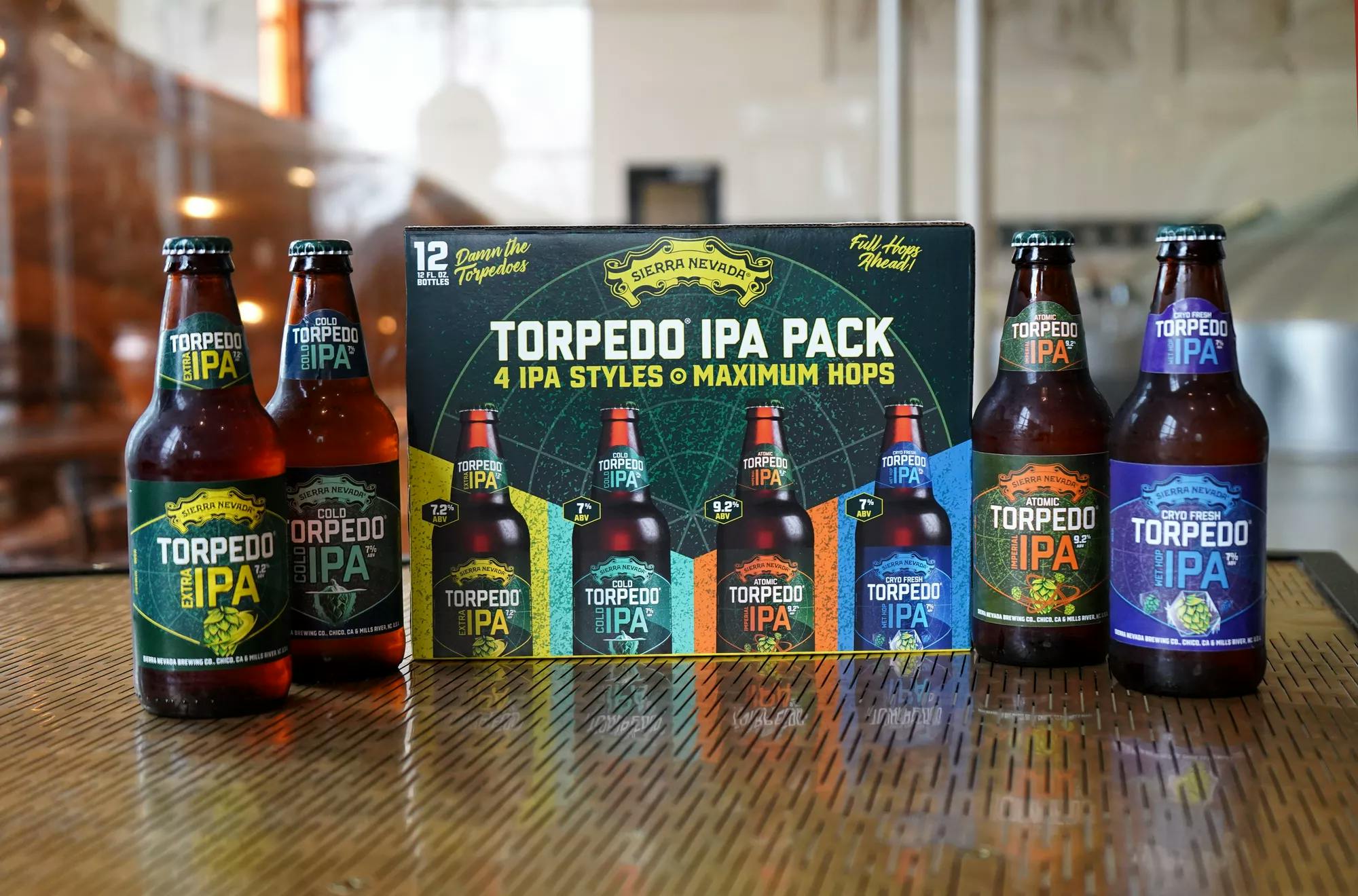 Torpedo IPA Pack sitting on a bar with each of the 4 varieties of bottles sitting in front of the packaging.